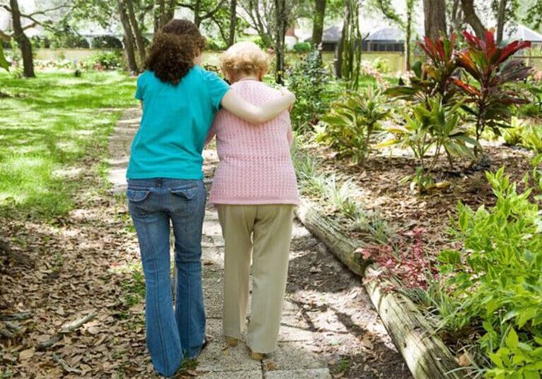 Two women walking arm in arm on a path.