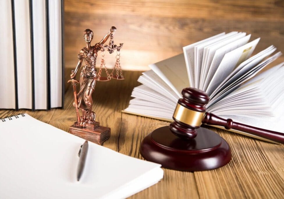 A gavel, statue of justice and books on the table.