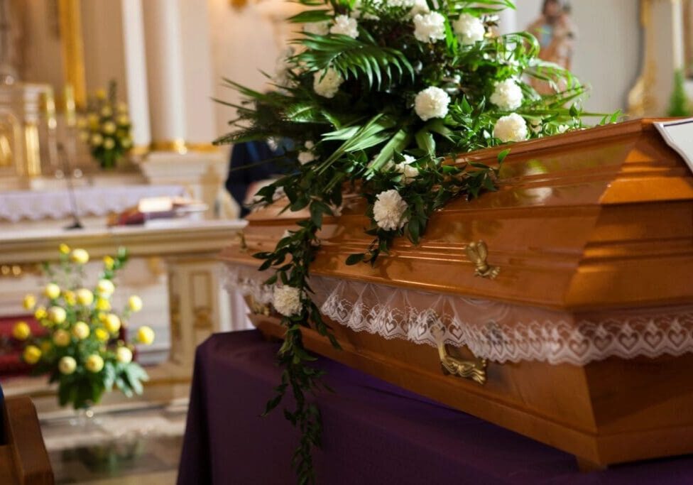 A wooden casket with flowers on top of it.